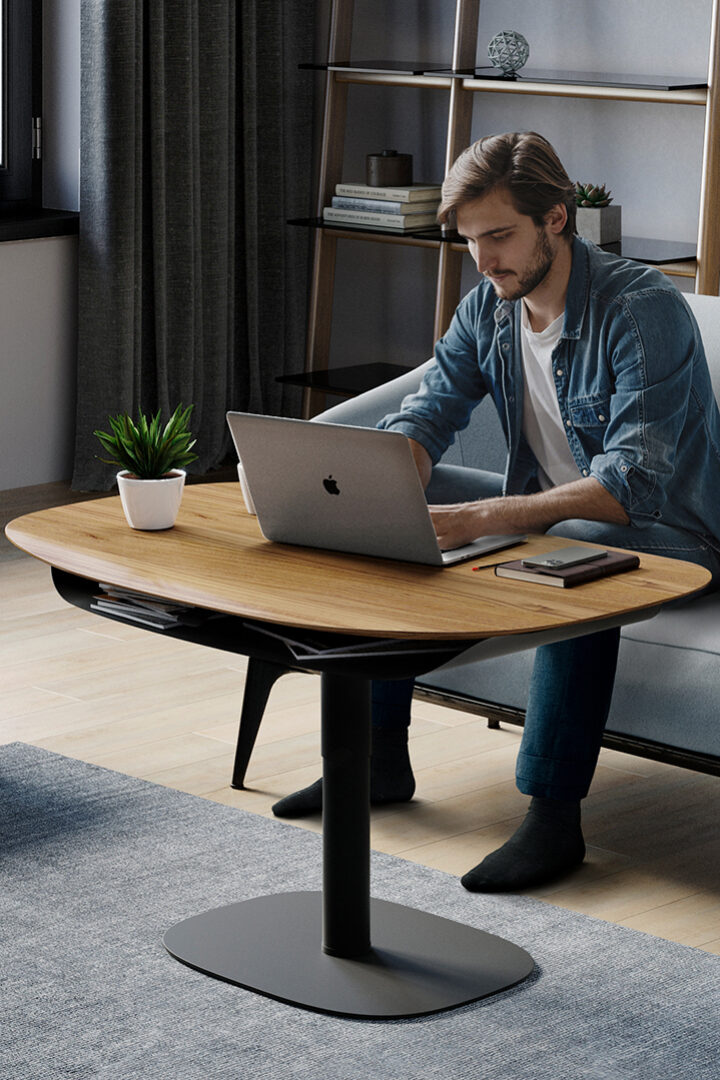 Man sitting on a sofa using the BDI Soma height adjustable coffee table to work on a laptop.
