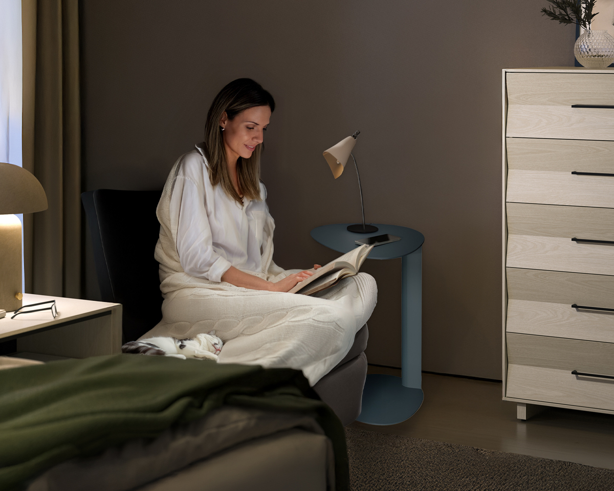 a woman reading in a chair in the corner of the bedroom