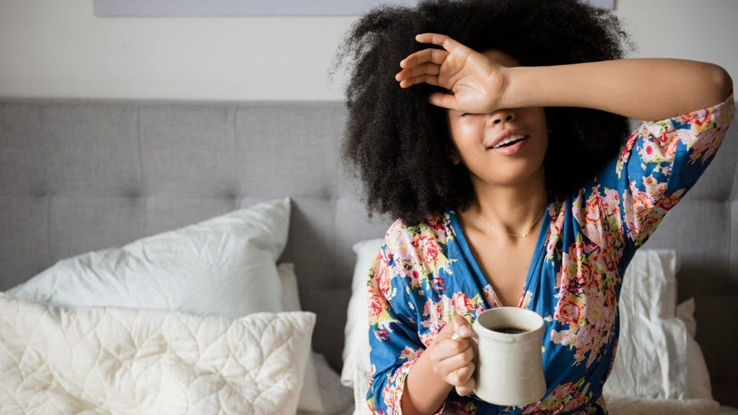 Woman waking up and starting her day with a cup of coffee.