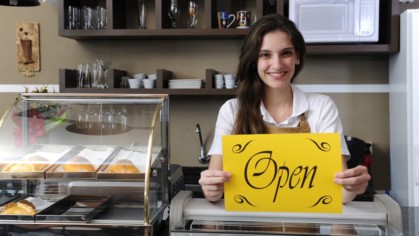 Independent and local female business owner holding an Open sign