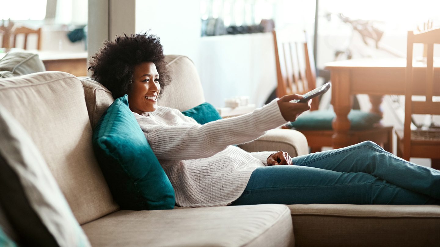 Woman relaxing on the couch and channel surfing on the TV.