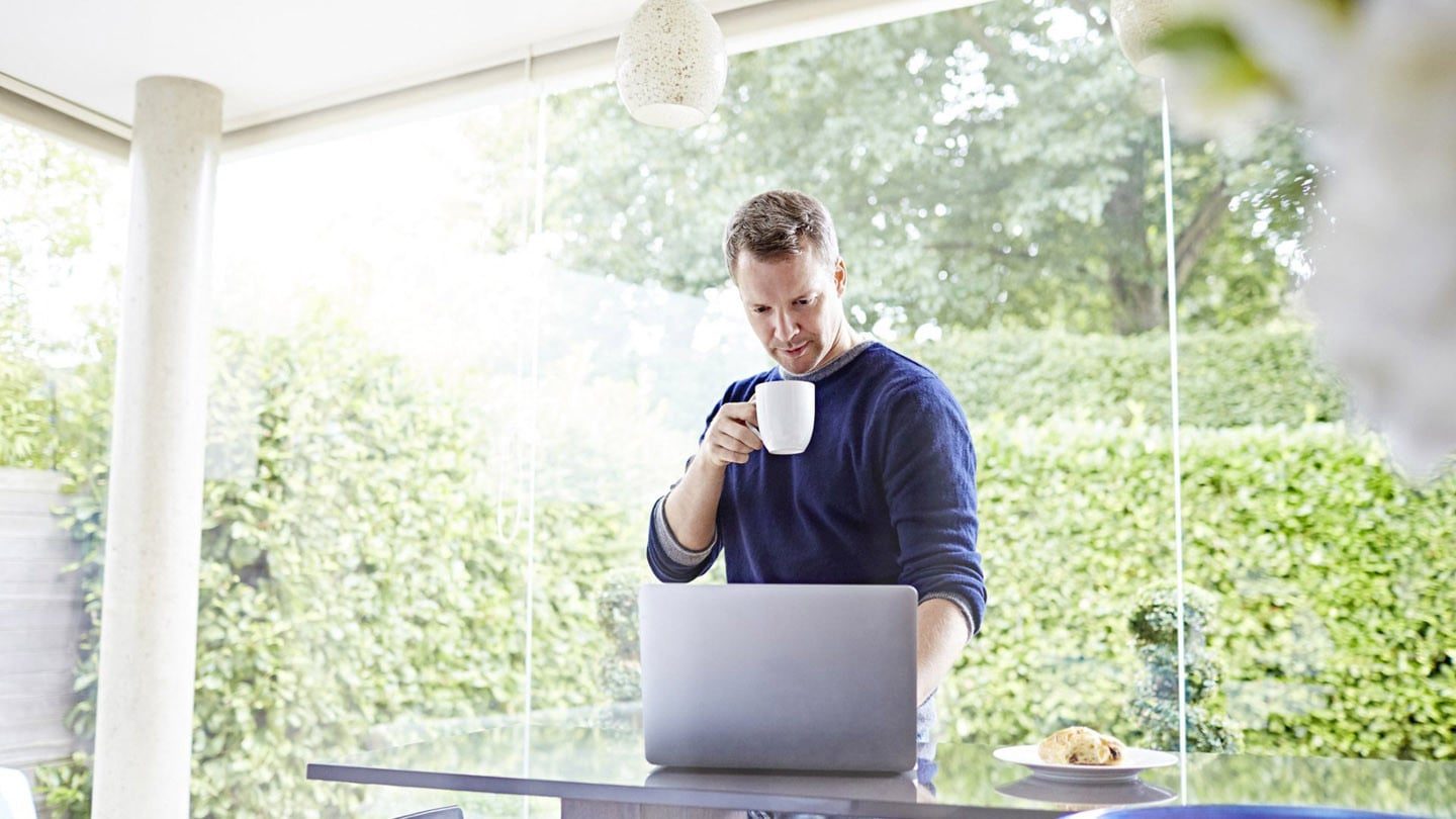 Man, drinking coffee and working from home in a well lit room.