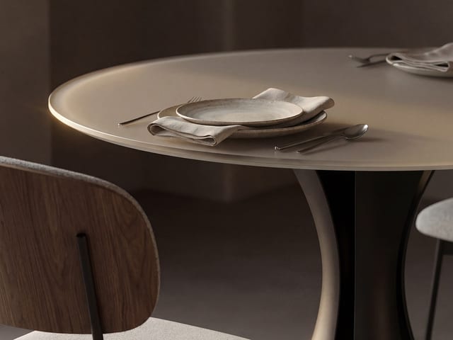 Close-up of the Bloom 7720 48-inch round dining table by BDI, highlighting the Oyster satin-etched glass top and Black sculptural steel base.