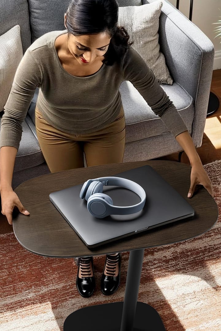 Close-up of a woman using the BDI Serif 1046 Lift-Top Table and demonstrating the ergonomic design, versatile height-adjustability, and wood craftsmanship in Toasted Oak.