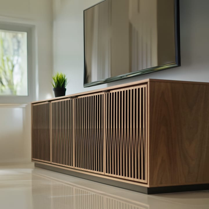 A clean and brightly lit living space is shown with an Elements 8703 media and storage cabinet by BDI Furniture, which has a rolling plinth base.  The Tune door pattern and washed oak finish are also featured.