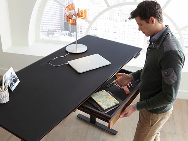 Attractive Millennial working from home on the Sequel Lift Standing Desk by BDI Furniture.